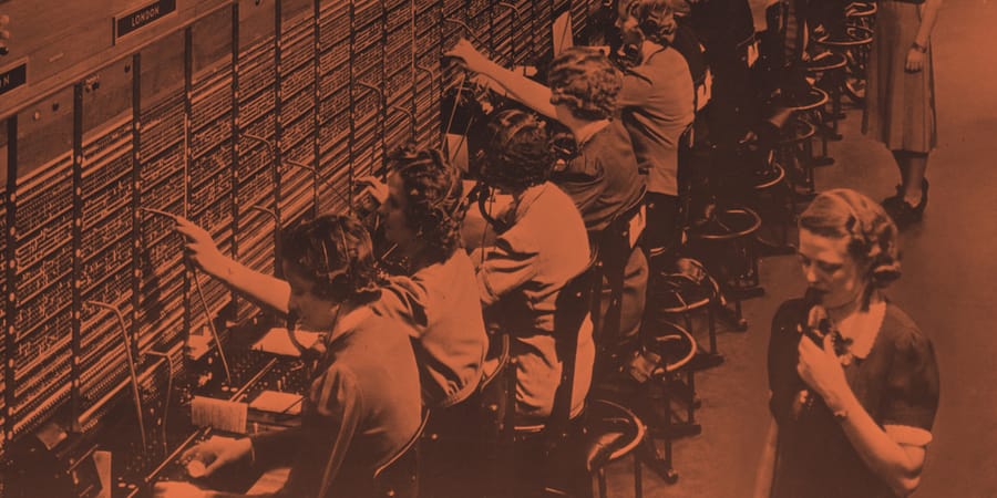 Bell System telephone switchboard with operators patching connections between distant exchanges