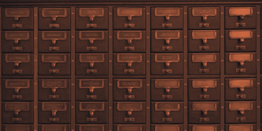 Wall of labelled library card-catalog drawers, each one closed until someone needs what is inside
